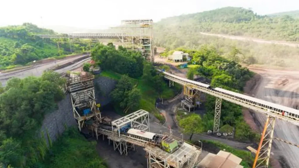 Fasilitas infrastruktur tambang batubara dengan conveyor belt di area hijau, ilustrasi bisnis energi PT Astrindo Nusantara Infrastruktur Tbk (BIPI)