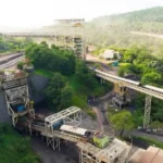Fasilitas infrastruktur tambang batubara dengan conveyor belt di area hijau, ilustrasi bisnis energi PT Astrindo Nusantara Infrastruktur Tbk (BIPI)